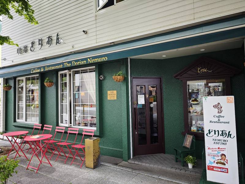赤いテーブルと椅子が並ぶ入口と、どりあんの看板